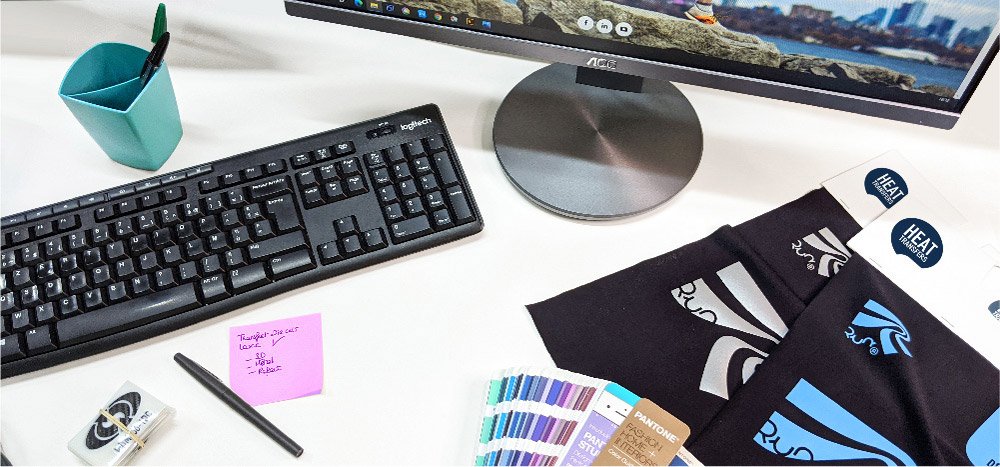 Desk with a Pantone colour swatch and t-shirts printed with textile transfers