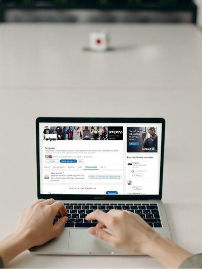 Person browsing the Seripress LinkedIn page and a job listing on a laptop