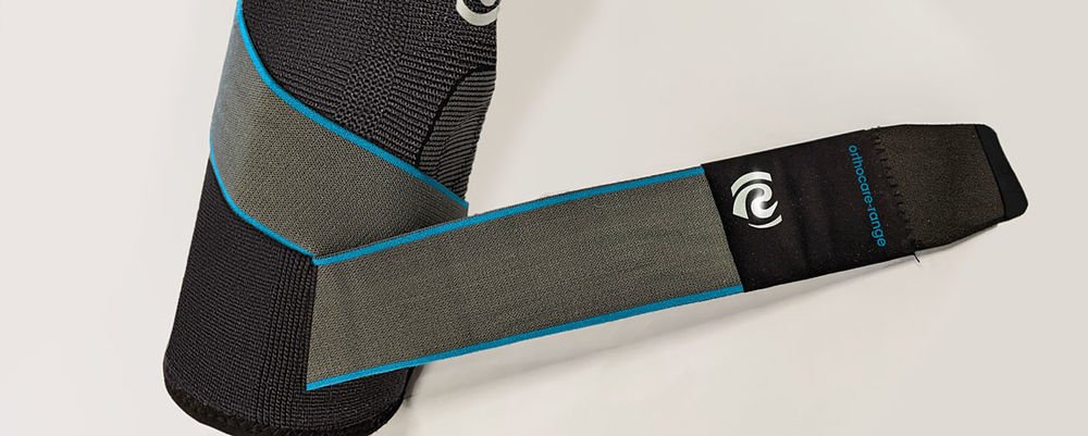 Genouillère orthopédique grise et noire avec liseré bleu, gamme Orthocare