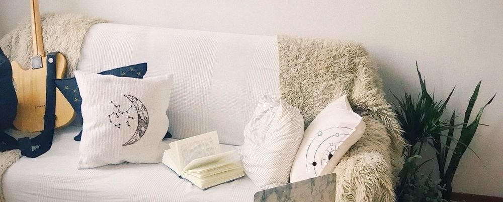 Coussins blancs imprimés de motifs lune et constellations sur un canapé
