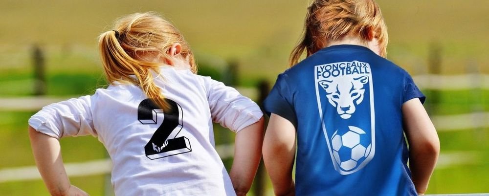 Deux fillettes de dos portant des t-shirts floqués d'un numéro et d'un blason de football