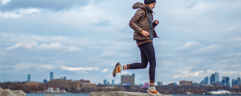 Runner wearing a branded puffer jacket and leggings by the water