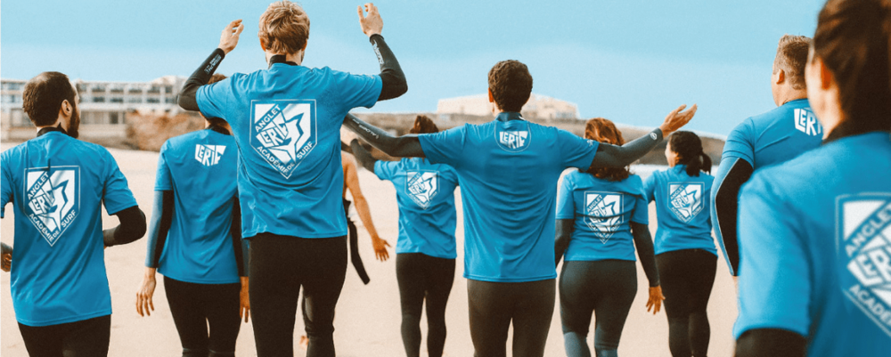 Group wearing blue t-shirts printed with a surf club crest