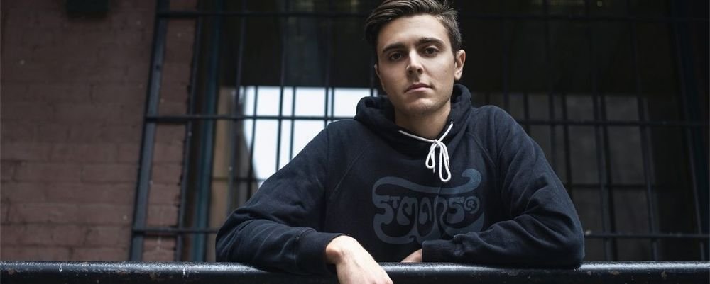 Man wearing a black hoodie printed with a script logo