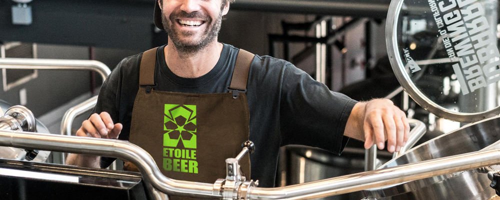 Brown apron printed with the "Etoile Beer" logo worn by a brewer