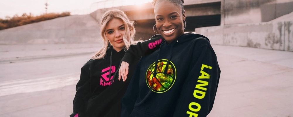Two women wearing black hoodies printed with colourful transfers