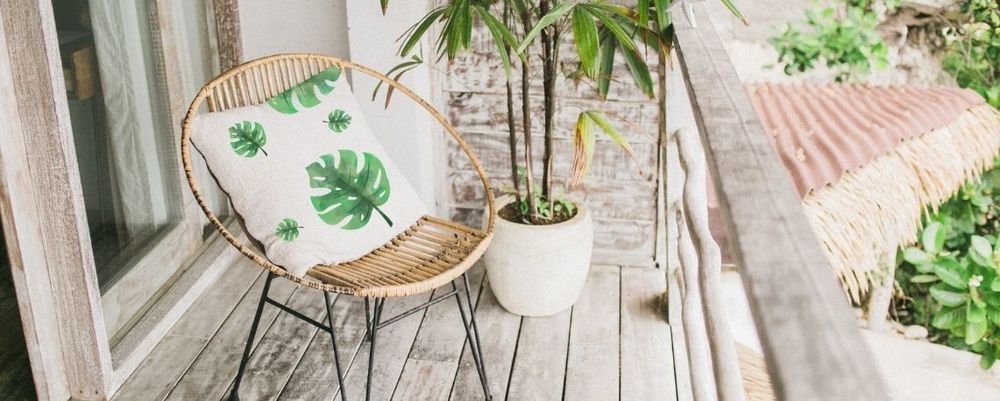 White cushion printed with green tropical leaves on a rattan chair