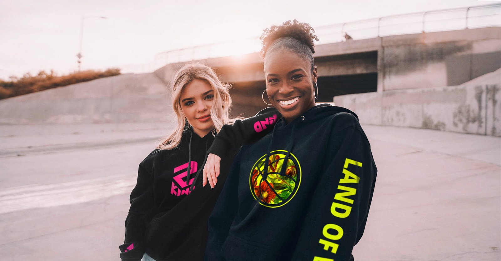 Two women wearing custom black hoodies with pink and yellow fluo logos